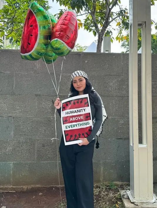 Rachel Vennya tampil dengan baju serba hitam sambil membawa balon semangka, ia juga mengenakan sorban di kepalanya. [@rachelvennya]