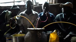 Sejumlah pria menggunakan selang kecil meminum air beralkohol dari pot yang disebut Busaa di daerah Nairobi, Kenya, Rabu (8/11). Bir tradisonal Kenya ini cukup populer di kalangan masyarakat kelas bawah. (AFP Photo/Simon Maina)