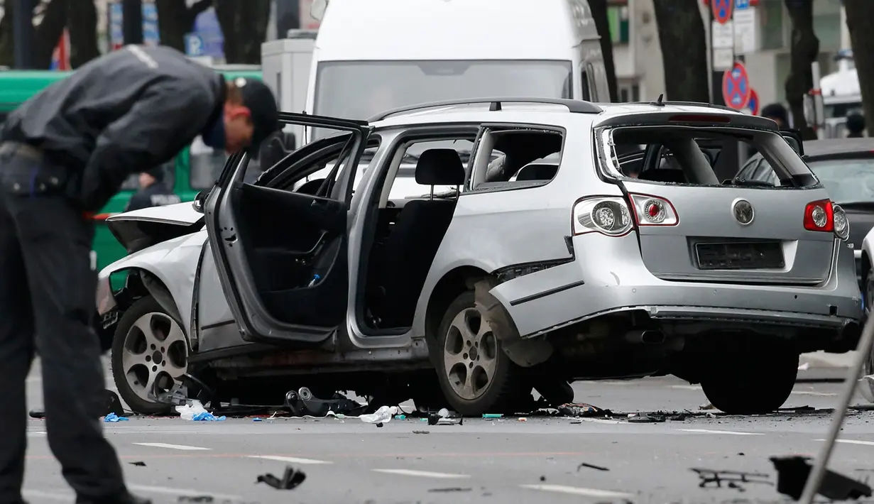 Petugas kepolisian memeriksa bangkai mobil Volkswagen yang rusak di Berlin , Jerman, (15/3). Warga Jerman di gegerkan oleh sebuah mobil yang tiba meledak di pusat kota Berlin. (REUTERS / Fabrizio Bensch)