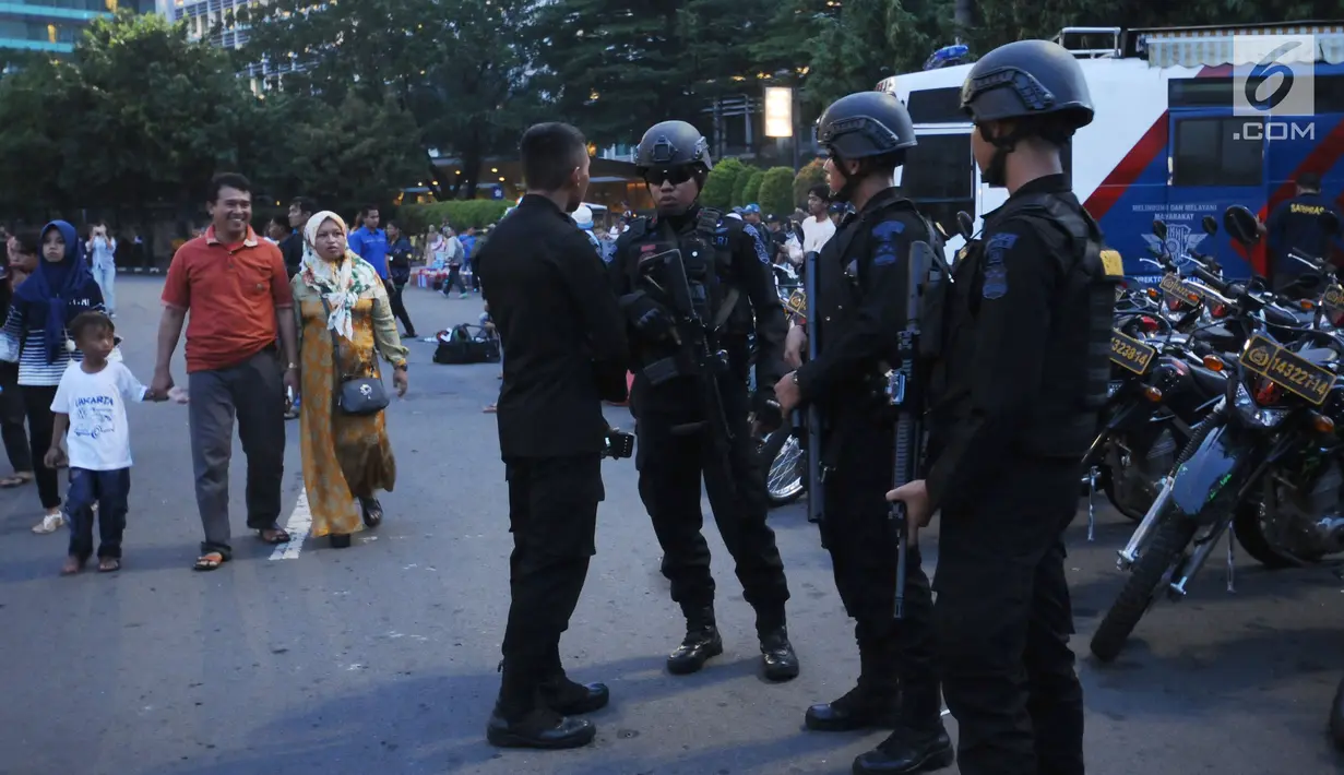 Personel Brimob melakukan koordinasi pengamanan jelang malam pergantian tahun di kawasan Bundaran Hotel Indonesia, Minggu (31/12). TNI dan Polri dikerahkan untuk mengamankan malam tahun baru 2018 di Jakarta. (Liputan6.com/Helmi Fithriansyah)