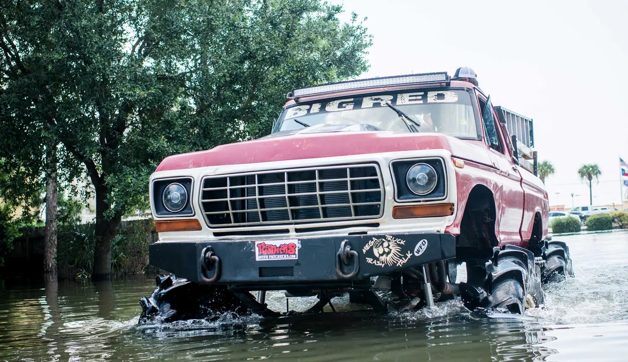 Warga menurunkan barangnya truk raksasa saat kembali ke rumah mereka di Port Arthur, Texas, AS (1/9). Truk raksasa ini menjadi salah satu kendaraan yang diandalkan usai Badai Harley menghantam Texas. (AFP Photo/Emily Kask)