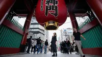 Seorang turis asing melihat ke dalam untuk melihat bagian dalam lentera terkenal di gerbang kuil Buddha Sensoji di distrik hiburan Asakusa, Tokyo, Jepang, Senin (17/10/2022). Kuil ini menjadi salah satu destinasi favorit di Asakusa, sekitar 30 juta wisatawan datang ke tempat ini sepanjang tahunnya. (AP Photo/Hiro Komae)