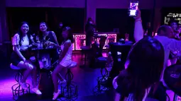 Pengunjung mendengarkan musik di bar kawasan hiburan Patpong, Bangkok, Thailand, Rabu (1/7/2020). Mulai 1 Juli, bar di Bangkok kembali diizinkan buka setelah pengurangan pembatasan untuk menghentikan penyebaran virus corona COVID-19. (Lillian SUWANRUMPHA/AFP)
