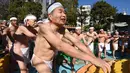 Penganut Shinto melakukan pemanasan sebelum memasuki kolam renang es untuk berdoa dan memurnikan tubuh dan jiwa dalam ritual Upacara Penyucian di Tokyo, Minggu (10/01/2016). (AFP Photo/ Toru Yamanaka)