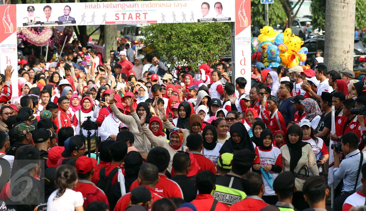 Peserta melambaikan tangan saat Kirab Kebangsaan Indonesia Raya di Cibinong, Kab Bogor, Minggu (14/5). Kirab diikuti puluhan organisasi kepemudaan se Kabupaten Bogor. (Liputan6.com/Helmi Fithriansyah)