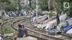Sejumlah tunawisma beraktivitas di dekat gubuknya yang berada di bantaran rel kereta api kawasan Senen, Jakarta, Minggu (14/2/2021). Setelah sempat ditertibkan, puluhan bangunan semipermanen yang beratapkan terpal dan beralas kardus milik tunawisma kembali menjamur. (merdeka.com/Iqbal S. Nugroho)