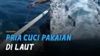 Seorang pria yang diketahui awak kapal melakukan aksi ekstrem mencuci pakaian di laut.