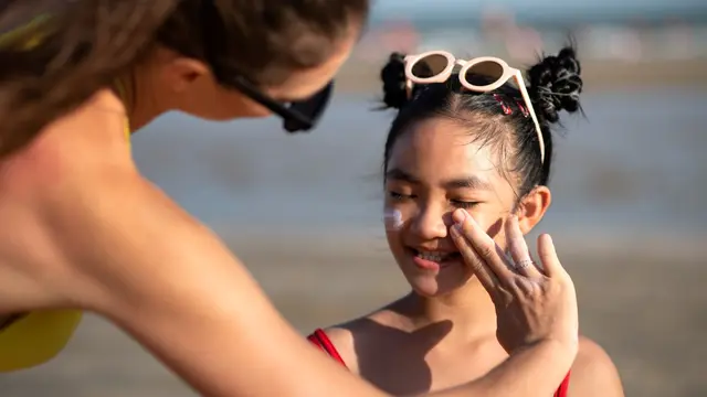 Seorang Ibu Sedang Mengoleskan Sunscreen Pada Anak