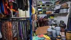 Seorang pedagang menata peci untuk dijual selama bulan suci Ramadan di dekat Masjid Sunan Ampel, Surabaya, Jawa Timur, pada Minggu 8 Maret 2026. Sepanjang Ramadan, kawasan sekitar Masjid Sunan Ampel, Surabaya, Jawa Timur, berubah menjadi pusat belanja dan kuliner yang kental dengan nuansa Timur Tengah. (JUNI KRISWANTO/AFP)