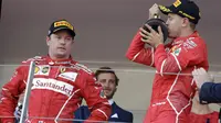Pebalap Ferrari, Sebastian Vettel merayakan kemenangan sementara Kimi Raikkonen hanya melihatnya dengan tatapan kosong pada F1 GP Monako, (28/5/2017). (AP/Claude Paris)