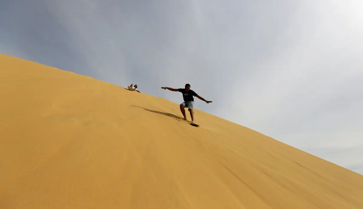 Sejumlah pengunjung berseluncur menggunakan papan sandboards di gurun pasir Wadi el-Rayan Fayoum, Mesir (18/11). Sandboarding ini hampir sama dengan snowboarding, yang membedakan adalah medannya di atas pasir. (Reuters/Mohamed Abd El Ghany)