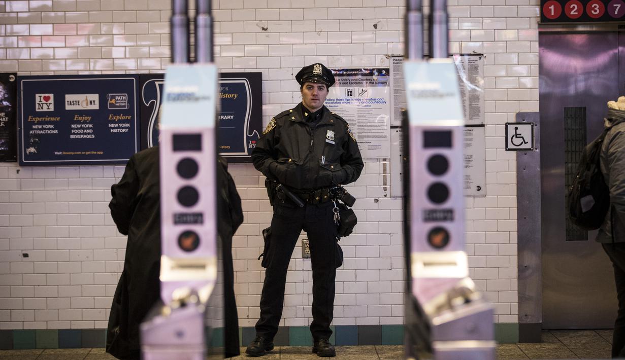Petugas kepolisian New York berjaga di pintu masuk stasiun kereta bawah tanah Times Square saat jam sibuk malam di New York City, Senin (11/12). Sebelumnya ledakan bom terjadi di terminal bawah tanah kawasan Manhattan. (Drew Angerer/Getty Images/AFP)