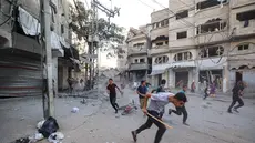 Orang-orang berlari mencari perlindungan setelah serangan Israel yang menargetkan sebuah bangunan di kamp pengungsi Palestina Bureij di Jalur Gaza tengah pada 19 Oktober 2025. (Eyad BABA/AFP)