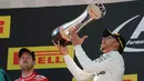 Pembalap Mercedes, Lewis Hamilton merayakan kemenangannya pada balapan F1 GP Spanyol di atas podium Sirkuit Catalunya, Minggu (14/5). Hamilton yang start dari posisi pole menyelesaikan 66 lap dengan gemilang. (AP Photo/Emilio Morenatti)