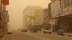 Mobil melaju di jalan selama badai debu di kota Nasiriyah Irak di provinsi Dhi Qar selatan (9/4/2022). Badai debu telah melanda sebagian besar Irak, meninggalkan puluhan orang di rumah sakit dengan masalah pernapasan. (AFP/Shwan Nawzad)