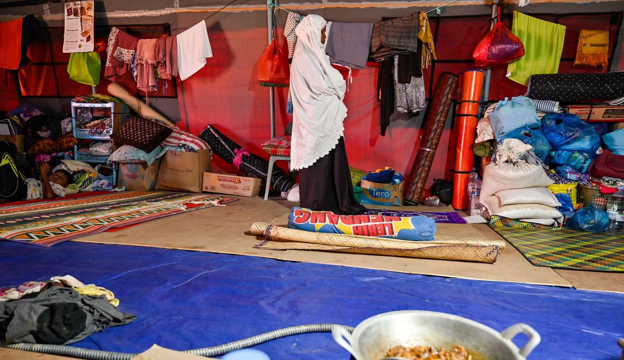 Mereka harus menjalani aktivitas sehari-hari, termasuk persiapan ibadah Ramadan, di dalam ruang yang sempit dengan sarana pendukung yang sangat minim. Tampak dalam foto, seorang wanita melakukan salat di dalam tenda yang menampung para korban banjir di Meurah Dua, Kabupaten Pidie Jaya, Provinsi Aceh, pada 21 Februari 2026, setelah banjir dan tanah longsor dahsyat melanda Sumatra, akhir November 2025 lalu. (CHAIDEER MAHYUDDIN/AFP)