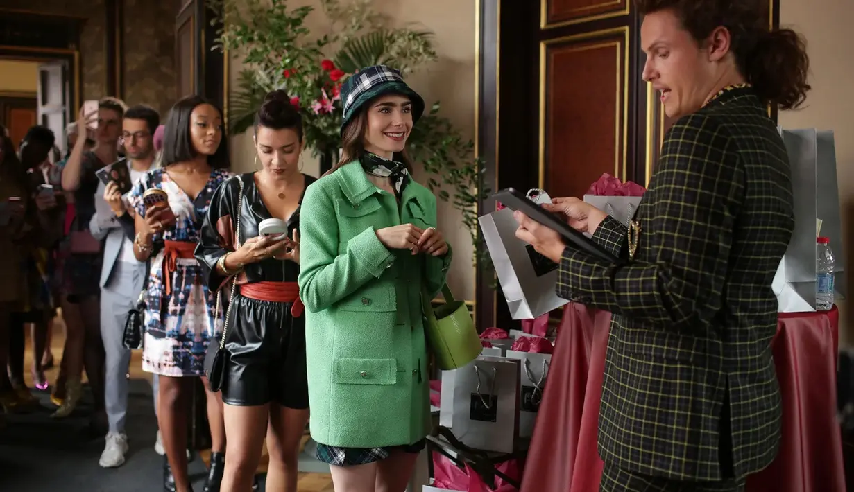 Ini adalah penampilan Lily Collins di Emily in Paris season 1. Ia mengenakan Chanel tweed jacket, plaid bucket hat, dan Staud mini bag. Foto: Netflix.