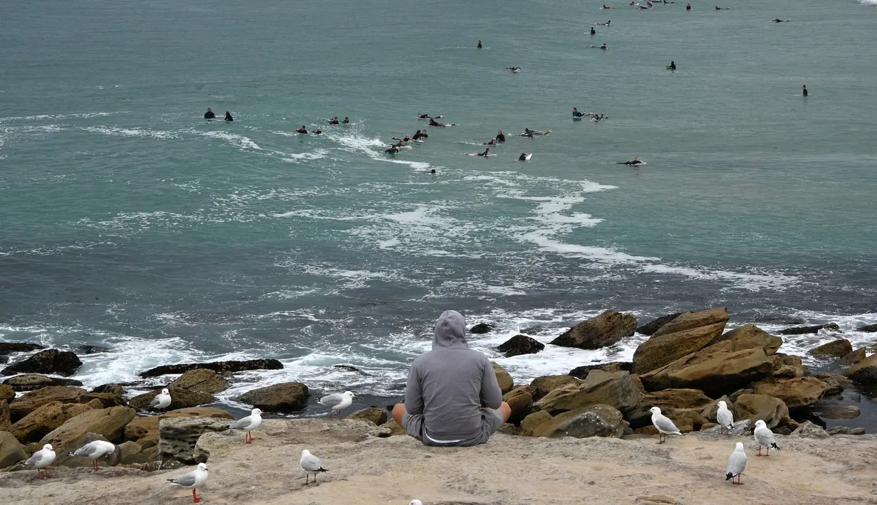 Seorang pria menyaksikan Pantai Maroubra yang dibuka kembali di Sydney (20/4/2020). Pihak berwenang di Sydney membuka kembali tiga pantai untuk aktivitas warga yang ingin berenang ataupun berselancar di tengah pembatasan sosial yang diberlakukan di tengah wabah Covid-19. (AFP/Saeed Khan)