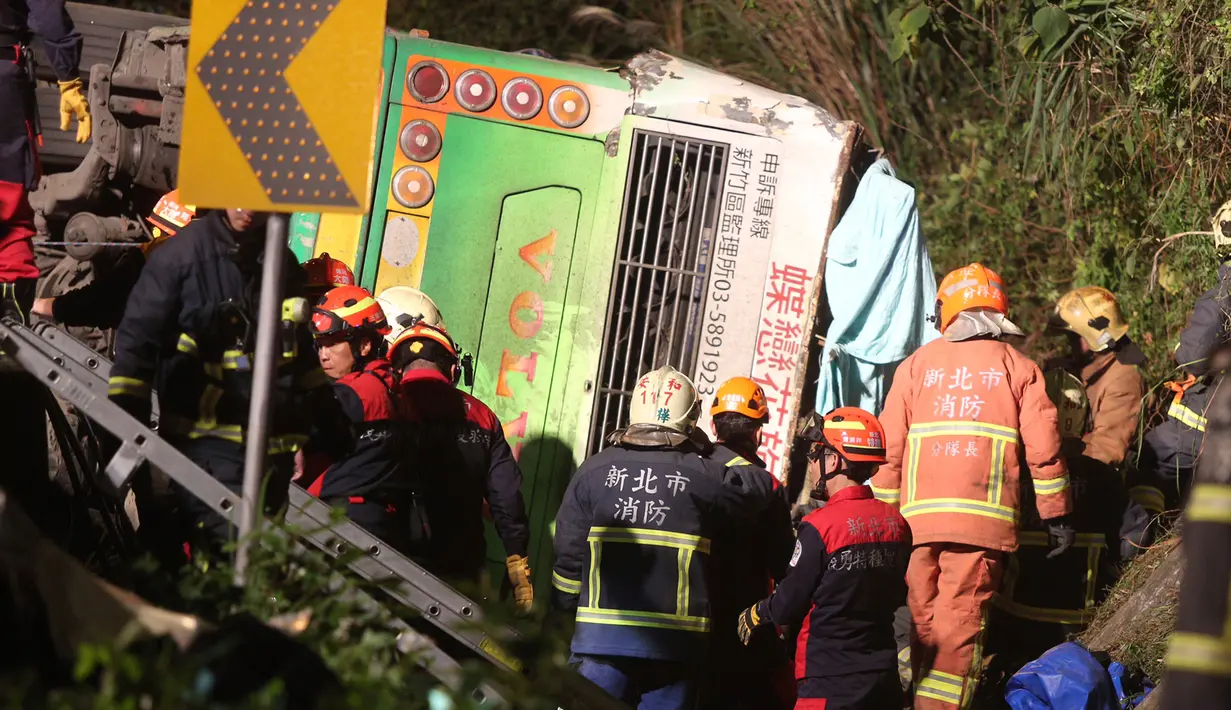 Tim SAR berusaha mengevakuasi bangkai bus pariwisata yang terbalik di ruas jalan dekat Taipe, ibu kota Taiwan, Selasa (14/2). Bus dilaporkan telah berusia 19 tahun dan dimiliki sebuah agen wisata yang melayani tur di seluruh Taiwan. (AP Photo)