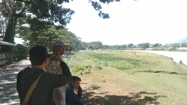 warga sekitar Sungai Palu menunjukkan tempat buaya berkalung ban kerap muncul, Sabtu (1/2/2020). (Foto: Liputan6.com/Heri Susanto)