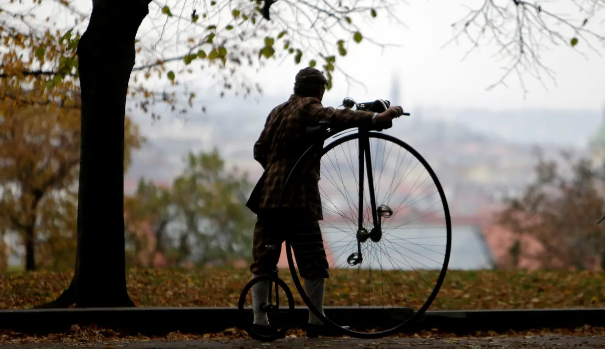 Seorang peserta mengenakan kostum sejarah mendorong sepeda penny farthing sebelum balapan penny farthing tahunan dimulai di Praha, Republik Ceko (5/11). (Reuters/David W Cerny)