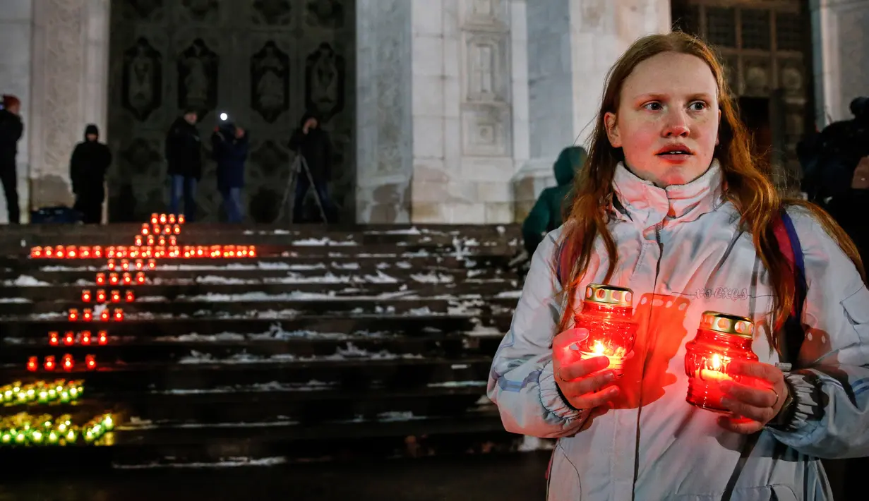 Seorang memegang lilin di depan Katedral Kristus Juruselamat Moskow, Rusia, Senin (12/2). Pesawat Saratov Airlines jatuh setelah lepas landas dari Bandara Domodedovo pada hari Minggu, 11 Februari 2018. (Maxim ZMEYEV / AFP)