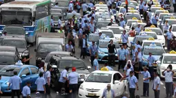 Para sopir taksi yang melakukan demo membakar ban dan juga memblokir jalan tol dalam kota, Mampang, Jakarta, Selasa (22/3). Terlihat asap membumbung tinggi dari ban yang terbakar sebagai wujud aksi anarkis sopir taksi. (Liputan6.com/Johan Tallo)