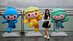 Seorang wanita berpose di antara maskot Asian Games 2022 (Chenchen, Congcong, dan Lianlian) yang terletak di sepanjang Sungai Qiantang di Hangzhou, Zhejiang, China pada 22 September 2023 waktu setempat. (AFP/Manan Vatsyayana)