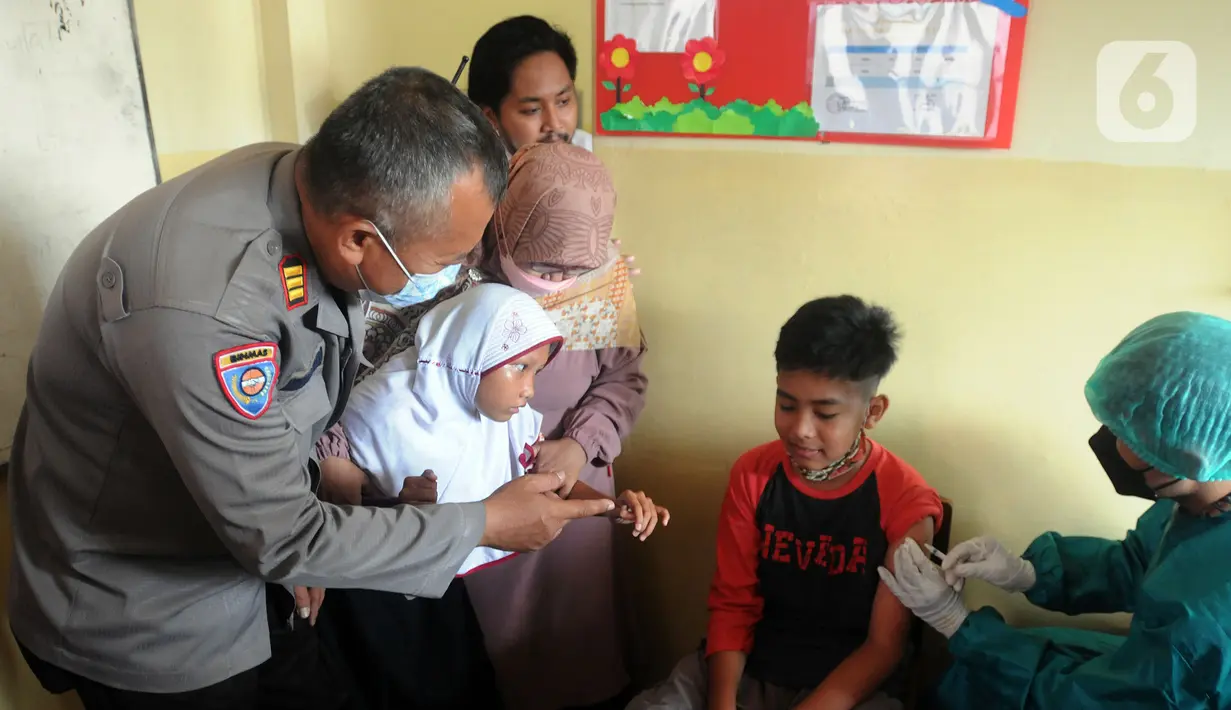 Anggota Polri dari Polsek Cinere menenangkan murid penyandang tunagrahita yang akan disuntik vaksin COVID-19 di SLB BC Manunggal Bhakti, Depok, Selasa (11/1/2022). Delapan murid SLB disuntik vaksin COVID-19 Sinovac yang merupakan rangkaian program Vaksinasi Merdeka. (merdeka.com/Arie Basuki)