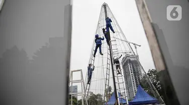 Pekerja memasang rangka pohon natal yang terbuat dari sampah botol plastik di Thamrin 10, Jakarta, Kamis (19/12/2019). Pemprov DKI sedang membangun dua pohon Natal setinggi 10 meter di Lapangan Banteng dan Thamrin menjelang perayaan Natal pada 25 Desember 2019 mendatang. (Liputan6.com/Faizal Fanani)