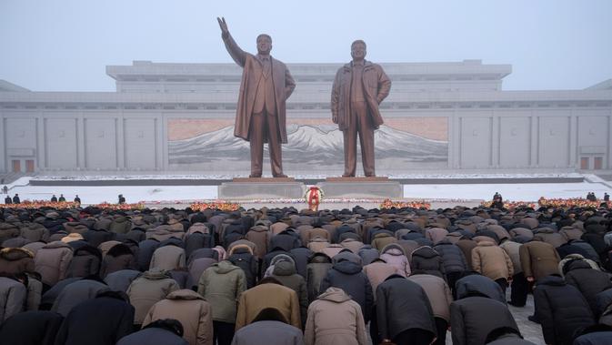 Penduduk Pyongyang memberi hormat di hadapan patung pemimpin Korea Utara Kim Il Sung dan Kim Jong Il selama Hari Peringatan Nasional di Bukit Mansu, Pyongyang (17/12).  Korea Utara tengah memperingati 7 tahun wafatnya  Kim Jong Il. (AFP Photo/Kim Won Jin)