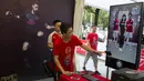 Seorang pekerja mengarahkan fans Arsenal untuk berfoto dengan gambar dua pemain The Gunners di Beijing, Jumat, (21/7/2017). Arsenal dan Chelsea akan bertanding dalam laga persahabatan. (AP/Ng Han Guan)