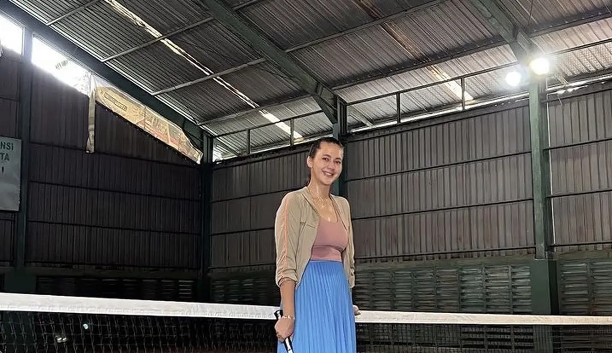 Saat tenis, ia memilih mengenakan tanktop cokelat di atas jaket crop topnya. Dipadukan rok plisket biru dan sneakers kuning dengan kaos kaki putih. (@paula_verhoeven)