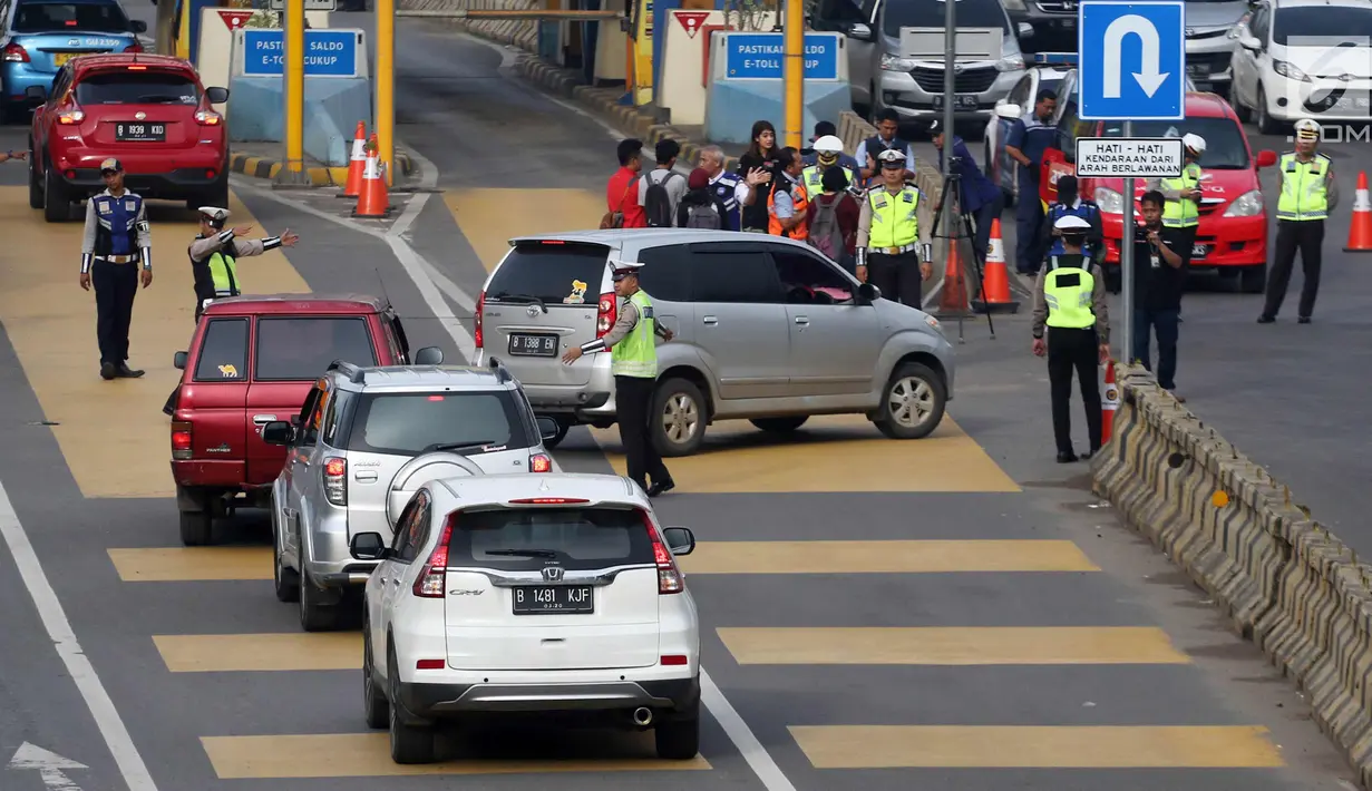 Petugas mengarahkan kendaraan berplat genap berputar balik di Gerbang Tol Bekasi Barat 1, Bekasi, Jawa Barat, Selasa (13/3). Hari kedua penerapan ganjil genap, masih banyak kendaraan berputar balik di gerbang tol tersebut. (Liputan6.com/Arya Manggala)