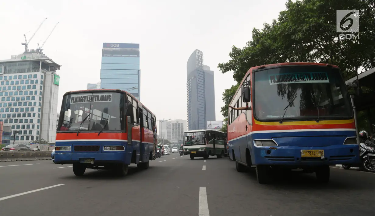Bus Kopaja dan Metromini melintas di Jalan Jenderal Sudirman, Jakarta, Rabu (4/7). Larangan bagi Kopaja dan Metromini melintasi jalan protokol selama Asian Games untuk mengurangi kemacetan dan polusi di jalan protokol. (Liputan6.com/Arya Manggala)