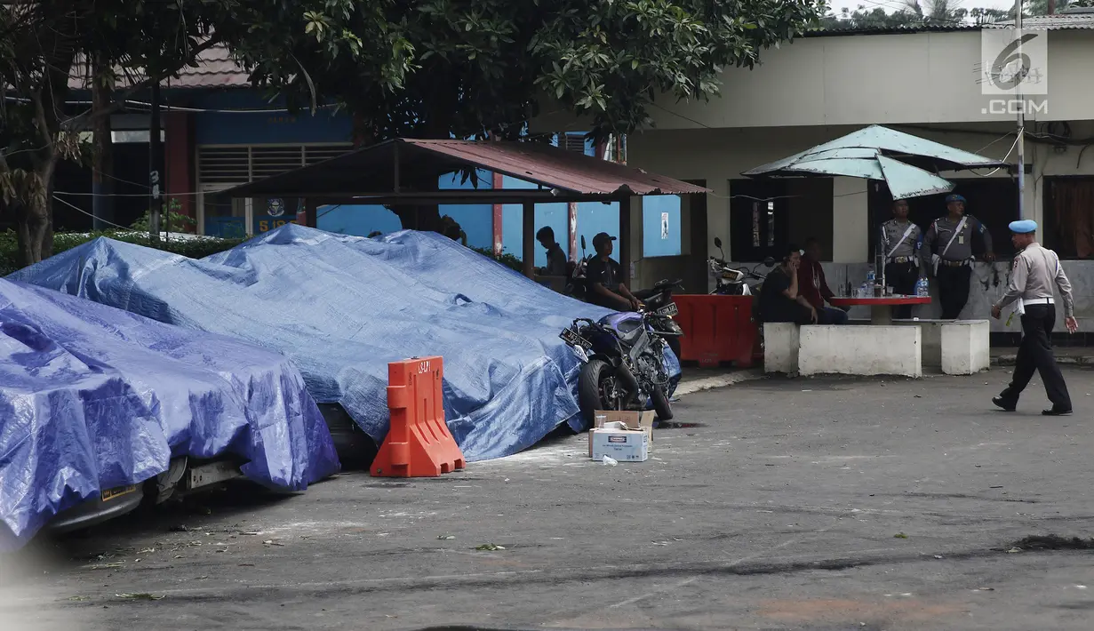 Terpal menutupi sejumlah mobil yang dirusak di Polsek Ciracas, Jakarta, Rabu (12/12). Selain mobil, bangunan Polsek Ciracas juga ikut dirusak massa. (Liputan6.com/Herman Zakharia)