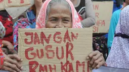 Seorang wanita lansia tampak membawa lembaran karton bertuliskan "jangan gusur rumah kami" di depan Balaikota DKI Jakarta, (11/9/14). (Liputan6.com/Herman Zakharia)