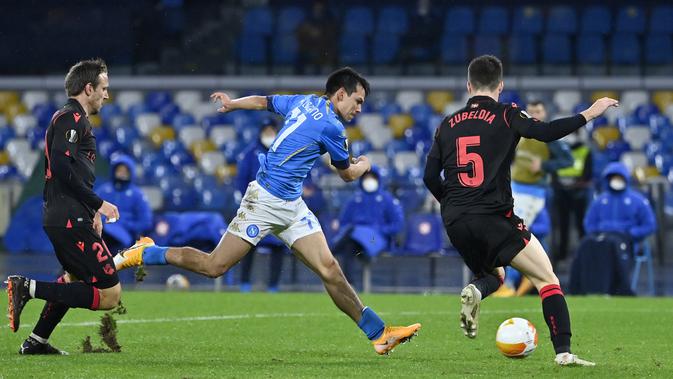 Penyerang Napoli, Hirving Lozano (tengah) menembak ke gawang melewati gelandang Real Sociedad Igor Zubeldia (kanan) Sociedad pada matchday terakhir Grup F Liga Europa di Diego Armando Maradona, Jumat (11/12/2020) dini hari WIB. Napoli bermain imbang 1-1 melawan Real Sociedad. (Alberto PIZZOLI / AFP)