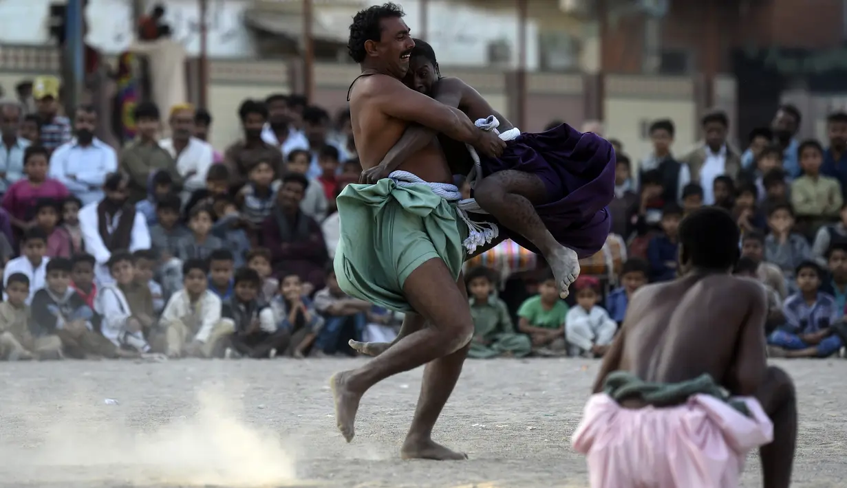 Pegulat bertarung selama turnamen gulat tradisional Sindhi Malakhra di kota pelabuhan Karachi, Pakistan pada Minggu (13/12/2020). Gulat kuno yang dimulai sejak 5.000 tahun lalu ini salah satu olahraga favorit di kalangan pria. (Photo by Asif HASSAN / AFP)