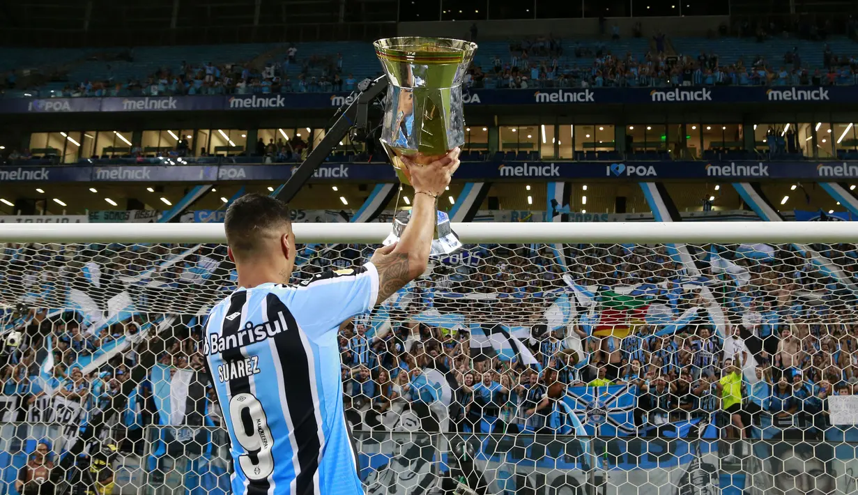 Pemain Gremio, Luis Suarez mengangkat trofi setelah memenangkan Gaucho Championship di Arena do Gremio Stadium, Porto Alegre, Brasil, 8 April 2023. (AFP/Silvio Avila)