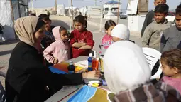 Inisiatif ini memberi ruang aman bagi mereka untuk menghadapi trauma akibat konflik berkepanjangan serta menuangkan ingatan mereka melalui seni lukis. Tampak dalam foto, anak-anak menyaksikan para perempuan muda melukis di pelabuhan Kota Gaza pada Kamis 12 Februari 2026. (Omar AL-QATTAA/AFP)