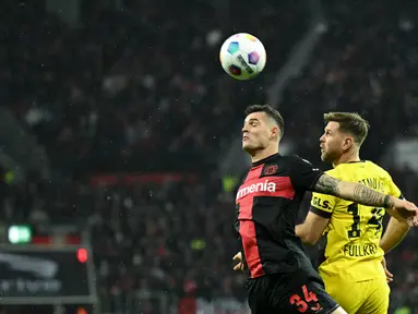 Gelandang Bayer Leverkusen #34 Granit Xhaka (kiri) berebut bola dengan penyerang Borussia Dortmund #14 Niclas Fuellkrug pada spieltag ke-12 Bundesliga 2023-24 di Bay Arena, Minggu (3/12/2023) malam WIB.
(INA FASSBENDER / AFP)