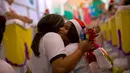 Narapidana perempuan (kanan) memeluk seorang sukarelawan dalam acara tahunan menghias sel menggunakan dekorasi bernuansa natal di Penjara Nelson Hungria, Rio de Janeiro, Kamis (13/12). (AP/Silvia Izquierdo)