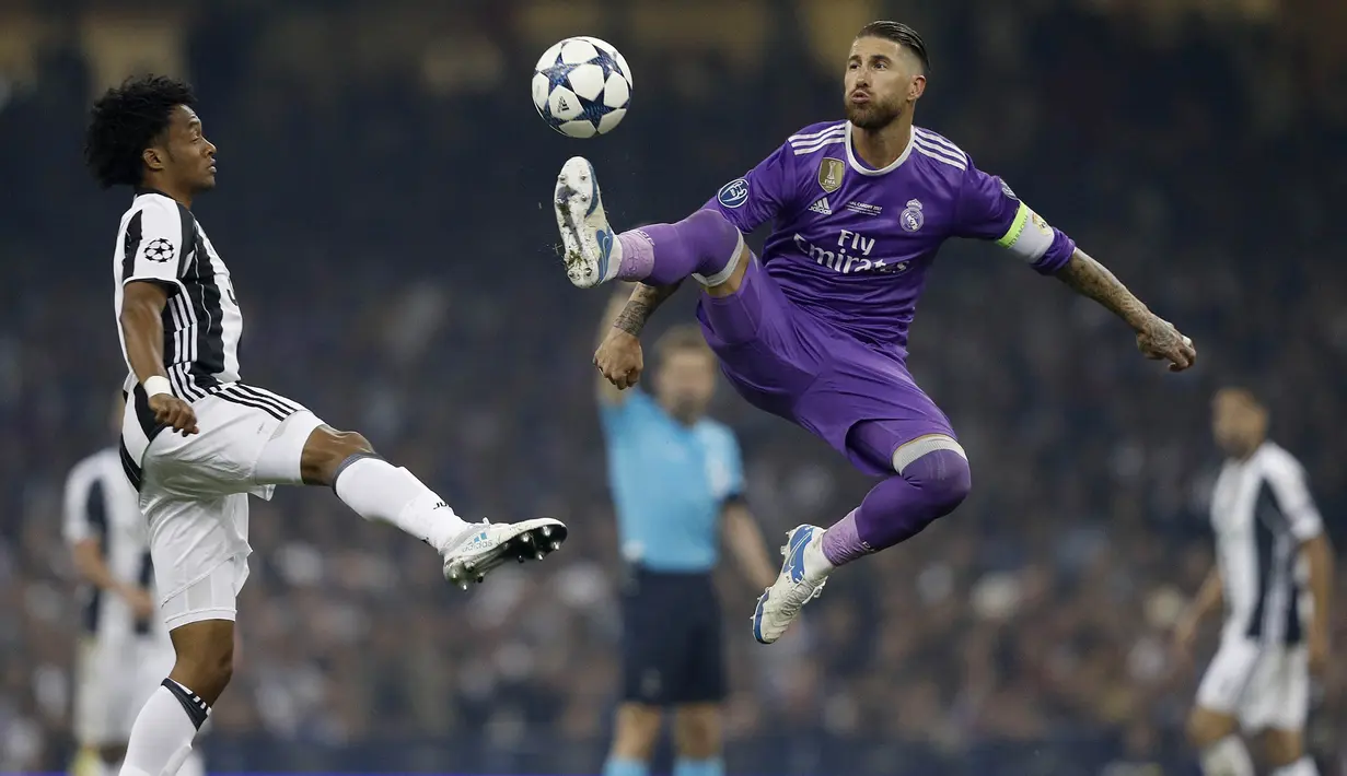 Kapten Real Madrid, Sergio Ramos, mengamankan bola dari gelandang Juventus, Juan Cuadrado, pada laga final Liga Champions di Stadion Stadion Millenium, Cardiff, Sabtu (3/6/2017). Madrid menang 4-1 atas Juventus. (AFP/Adrian Dennis)