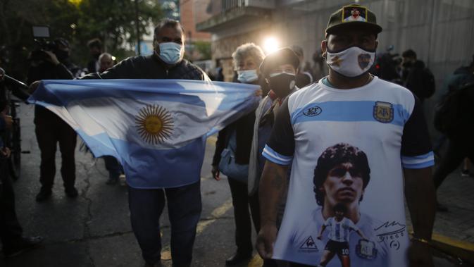 Penggemar sepak bola berkumpul di luar Clinica Olivos, tempat mantan bintang sepak bola Argentina Diego Maradona akan menjalani operasi, di Buenos Aires, Selasa (3/11/2020). Diego Maradona menjalani operasi hematoma subdural atau pembekuan darah di otak. (AP Photo/Natacha Pisarenko)
