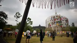 Pengunjung melihat dekorasi payung pada Festival Payung Indonesia 2018 di Taman Lumbini, Komplek Candi Borobudur, Magelang, Jumat (7/9). Festival yang digelar sejak 2014 ini bertujuan melestarikan payung tradisional yang mulai punah. (Liputan6.com/Gholib)