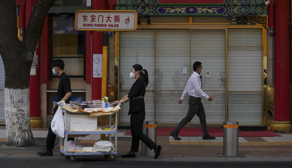 <p>Pekerja yang mengenakan masker mendorong troli yang berisi makanan untuk dibawa pulang melewati restoran hotpot yang tutup di Beijing pada Senin, 23 Mei 2022. Beijing memperpanjang perintah bagi pekerja dan siswa untuk tinggal di rumah dan memerintahkan pengujian massal tambahan pada hari Senin untuk membendung kasus COVID-19 yang kembali meningkat di ibu kota China. (AP Photo/Andy Wong)</p>