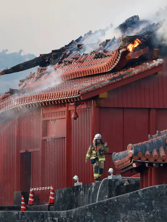 Petugas pemadam kebakaran terlihat di depan Kastil Shuri yang terbakar di Okinawa, Jepang selatan, Kamis (31/10/2019). Struktur yang saat ini berdiri merupakan rekonstruksi yang didasarkan atas rancangan awal dan foto-foto lama kastil bersejarah tersebut. (Jun Hirata/Kyodo News via AP)