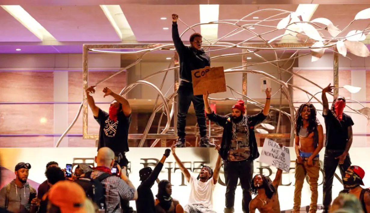Sejumlah pengunjuk rasa berkumpul di depan sebuah hotel saat demontrasi di daerah Charlotte, North Carolina, AS, Rabu (21/9). Pengunjuk rasa protes atas penembakan pria kulit hitam yang dilakukan oleh polisi. (REUTERS/Jason Miczek)