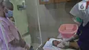 Pasangan orangtua baru memperhatikan saat perawat mempraktekan cara memandikan bayi di RSIA Tambak, Jakarta, Kamis (18/02/2021). Melatih para ibu baru untuk memandikan bayi pertama tersebut dilakukan dengan menerapkan protokol kesehatan ketat. (Liputan6.com/Herman Zakharia)